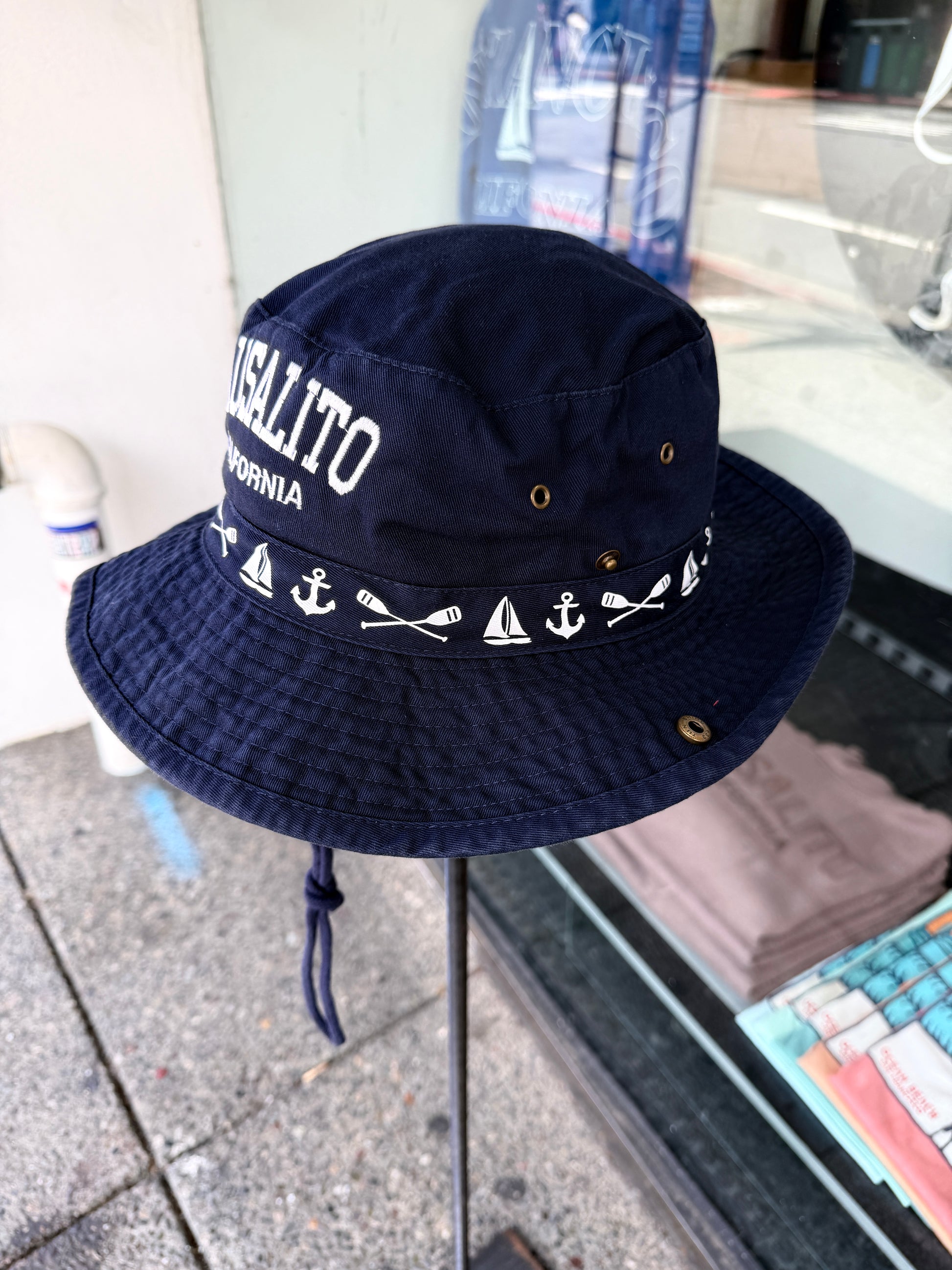 A side profile view of the navy blue Sausalito nautical bucket hat, showcasing its soft cotton construction, wide protective brim, sturdy stitched panels, and the clean white marine-themed embroidery wrapping around the front.