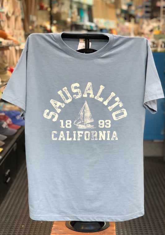 Washed denim blue t-shirt with a minimalist distressed white sailboat graphic, celebrating the simple joys of Sausalito sailing
