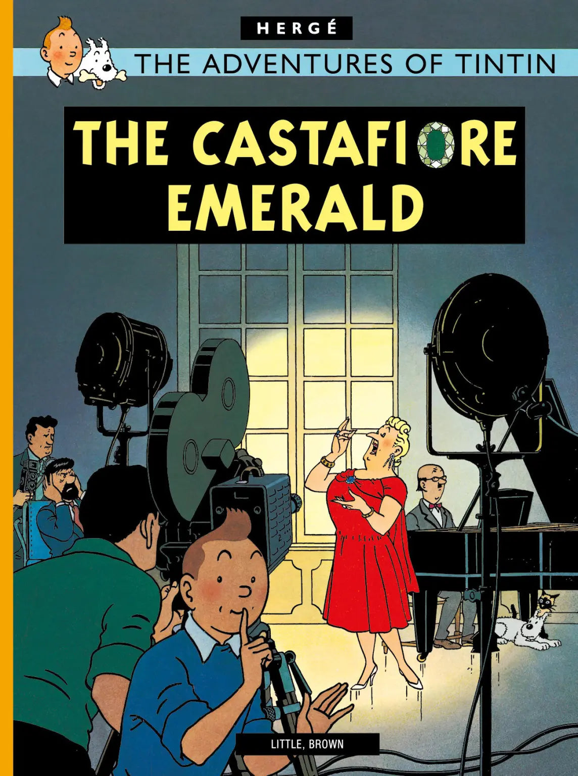 Comic book cover for The Castafiore Emerald. In the foreground, Tintin holds a finger to his lips in a "shush" gesture. In the background, the opera singer Bianca Castafiore is singing passionately on a stage with a pianist, under bright studio lights. Captain Haddock and other characters are visible in the wings, looking exhausted or annoyed.