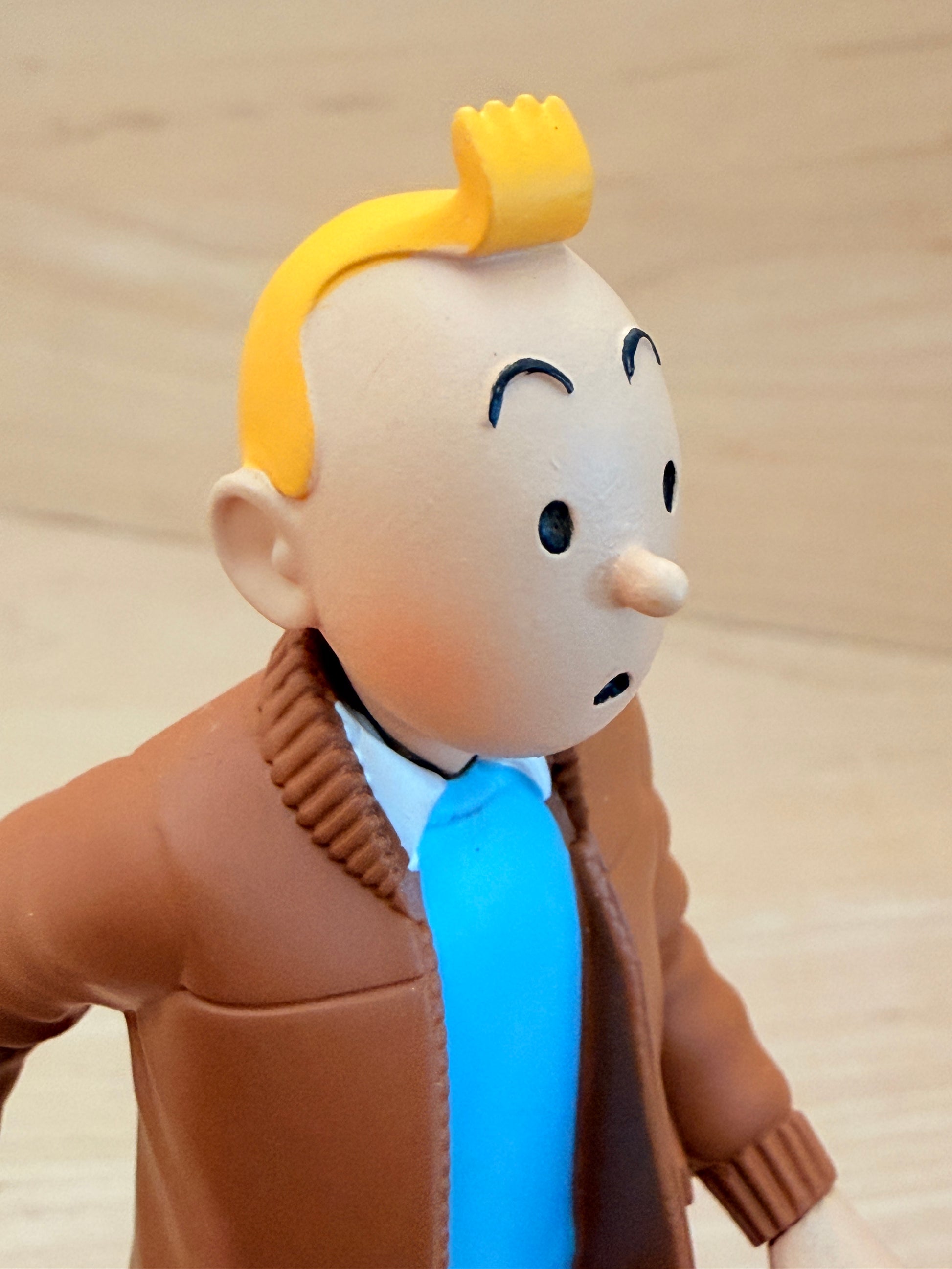 A close-up detail shot of the 12 cm Tintin Aviator Jacket resin figure, focusing on his classic quiff hairstyle, expressive face, and the fine hand-painted texture of the brown jacket collar and blue sweater.