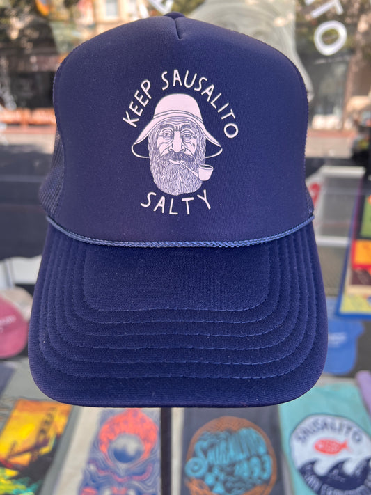 Keep Sausalito Salty Trucker Cap in navy blue featuring a white screen-printed graphic of a bearded fisherman in a rain hat with "Keep Sausalito Salty" text.