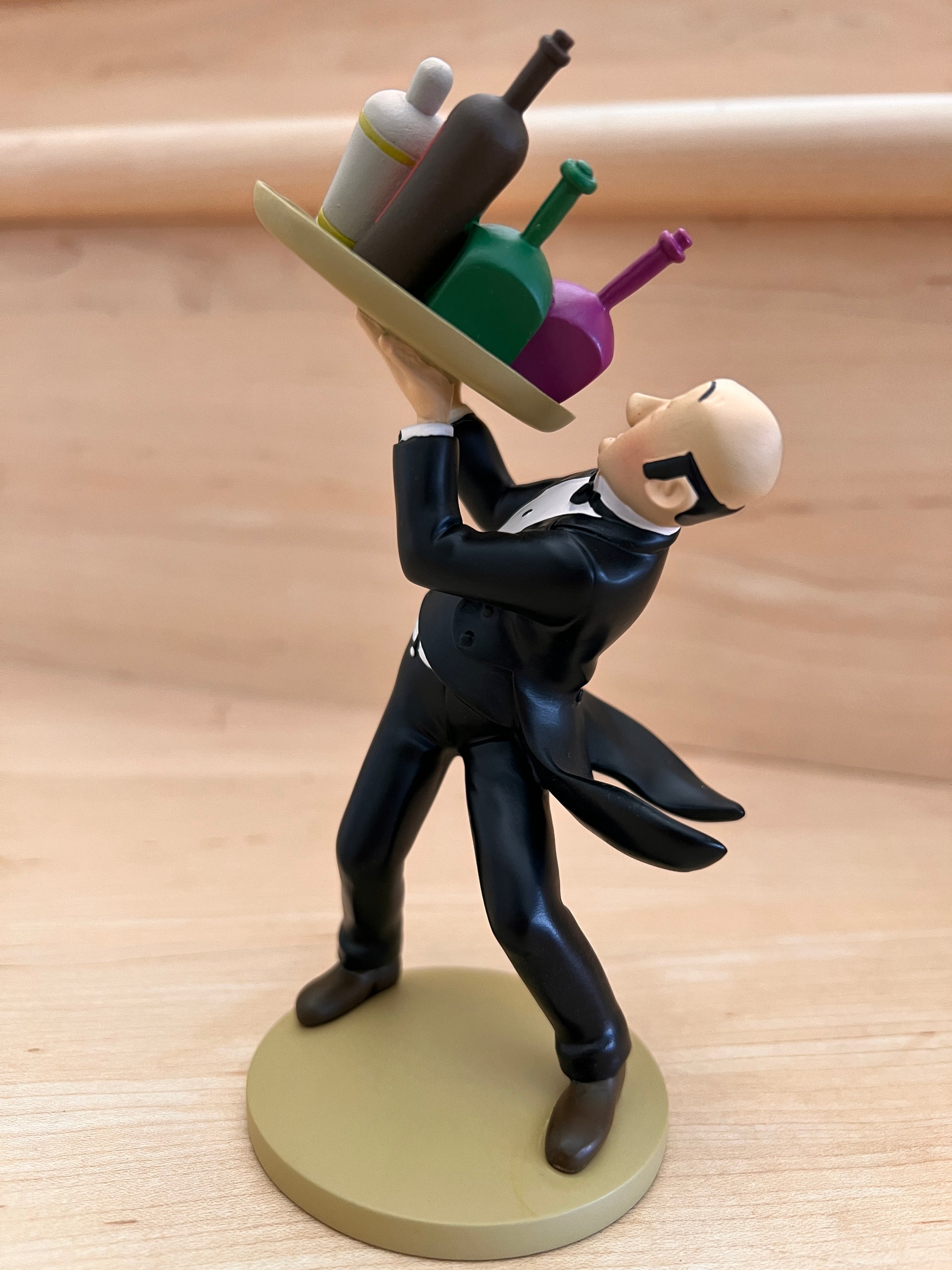 Official Tintin collectible resin figurine of Nestor the butler from The Castafiore Emerald, performing his famous "fancy footwork" while balancing a tray of colorful drink bottles.