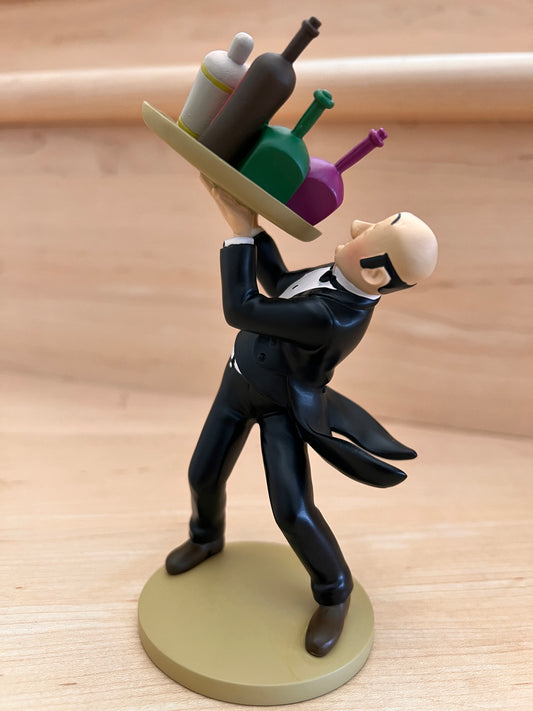 Official Tintin collectible resin figurine of Nestor the butler from The Castafiore Emerald, performing his famous "fancy footwork" while balancing a tray of colorful drink bottles.