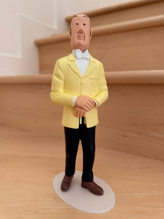 Impeccably dressed Tintinimaginatio Icons collection resin figurine of Nestor, the butler of Marlinspike Hall from The Adventures of Tintin. He is wearing his classic yellow double-breasted suit jacket, white shirt, and white bowtie, standing poised with his hands clasped calmly in front of him on a minimalist circular ba