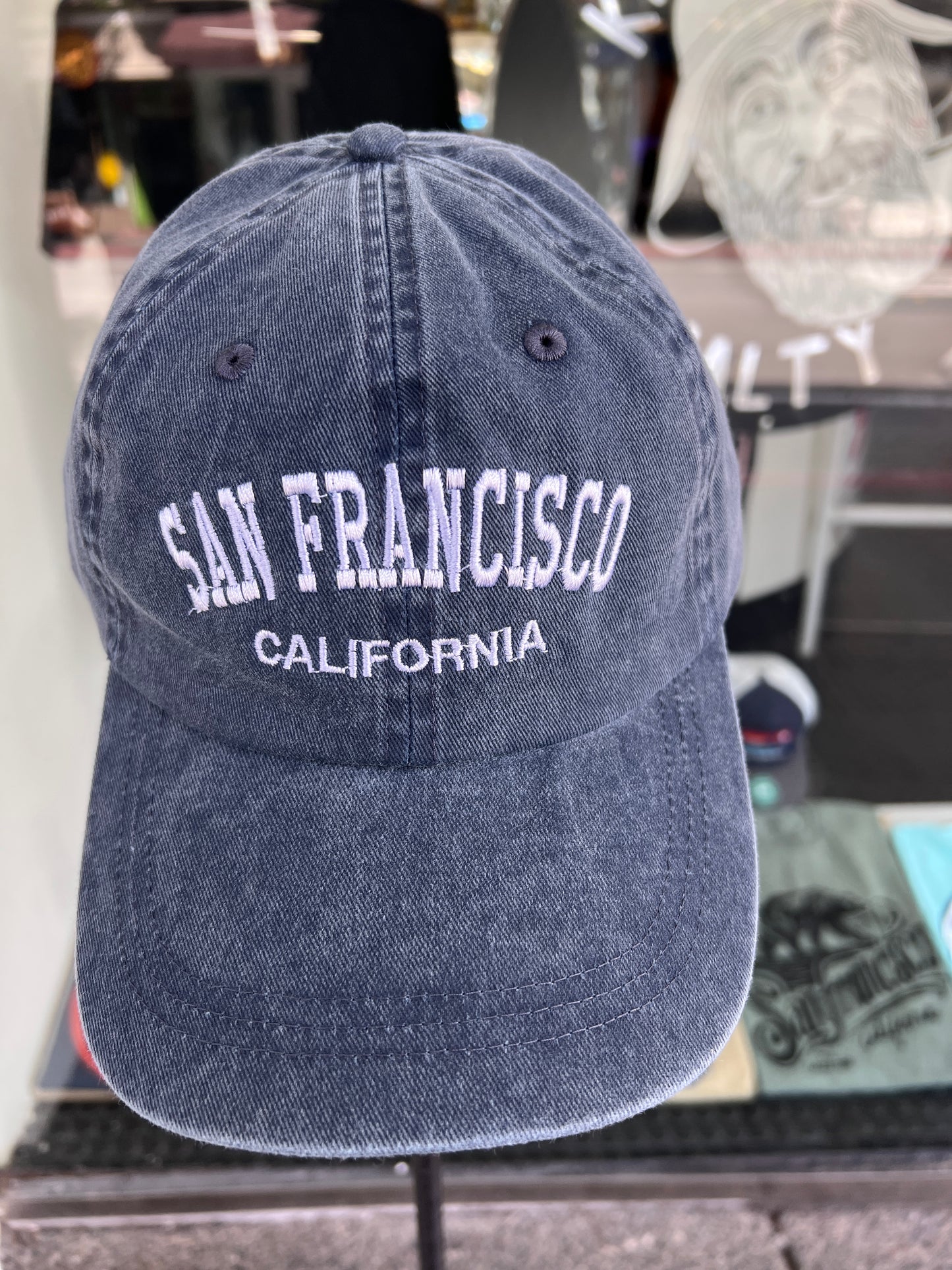 Front view of a dark navy blue washed cotton baseball cap featuring 'San Francisco' embroidered across the front in a bold white arched font with 'California' stitched directly underneath.