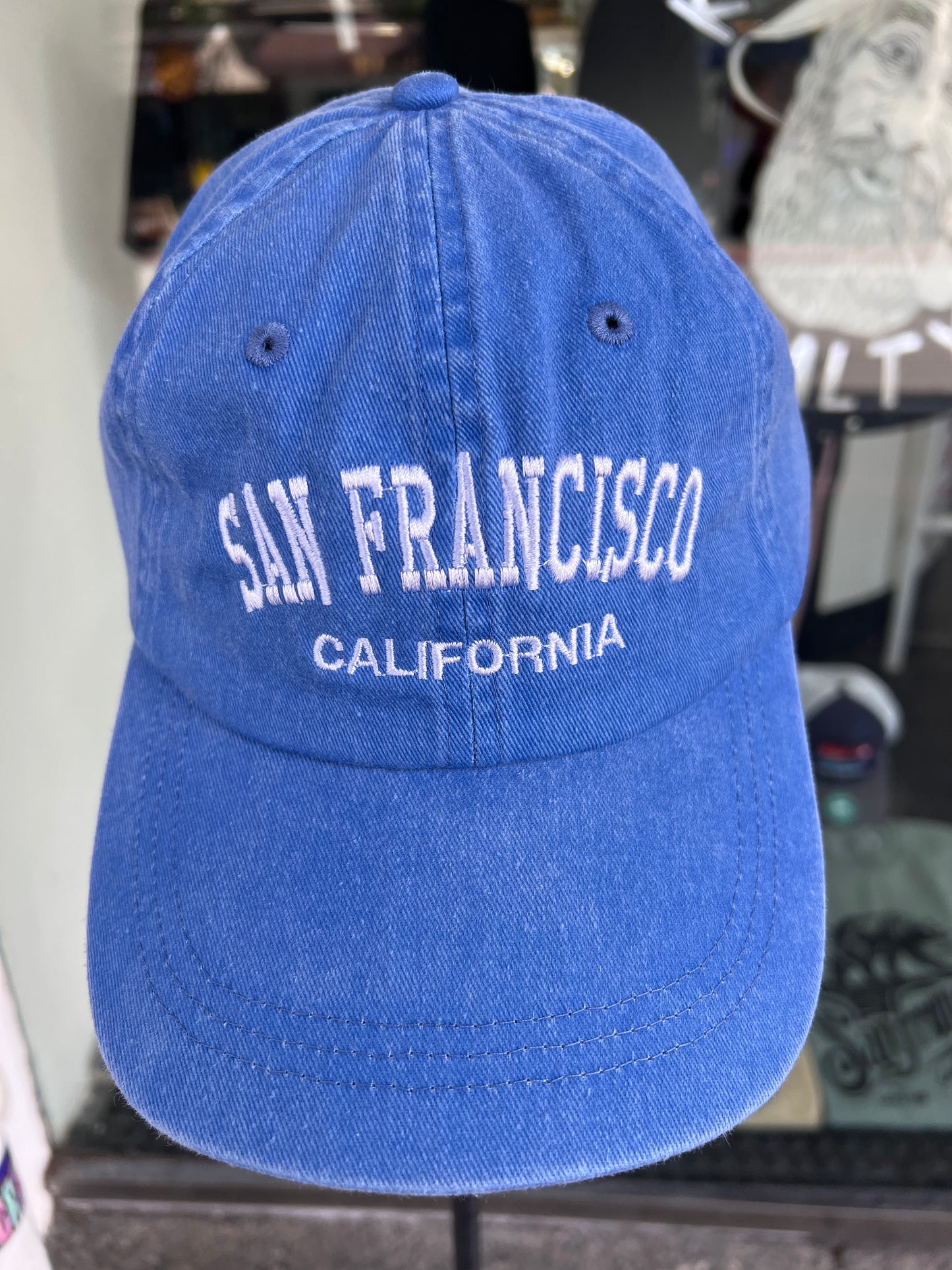 Front view of a royal blue washed cotton baseball cap featuring the words 'San Francisco' in a bold white arched font with 'California' embroidered directly underneath.