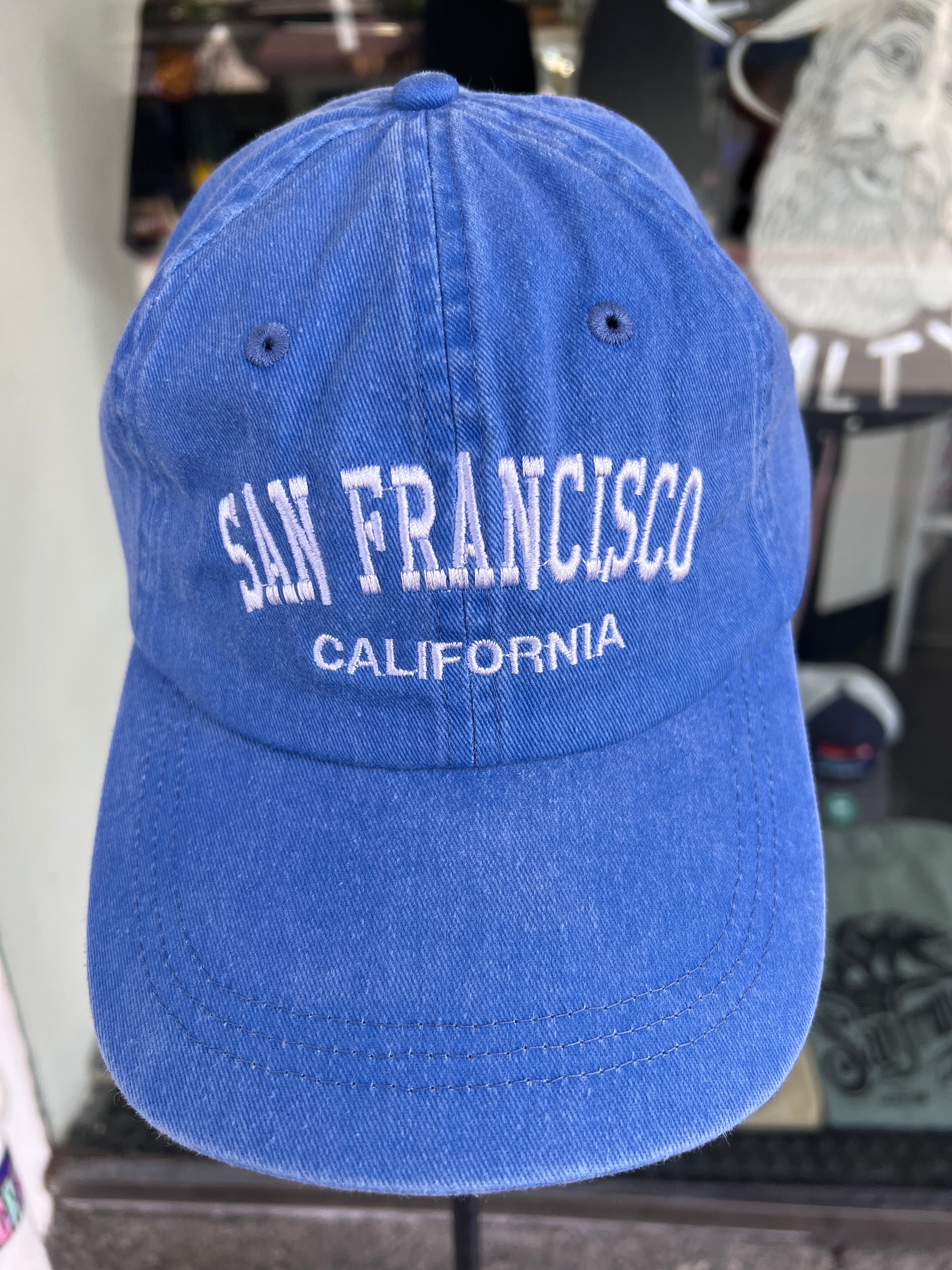 Front view of a royal blue washed cotton baseball cap featuring the words 'San Francisco' in a bold white arched font with 'California' embroidered directly underneath.