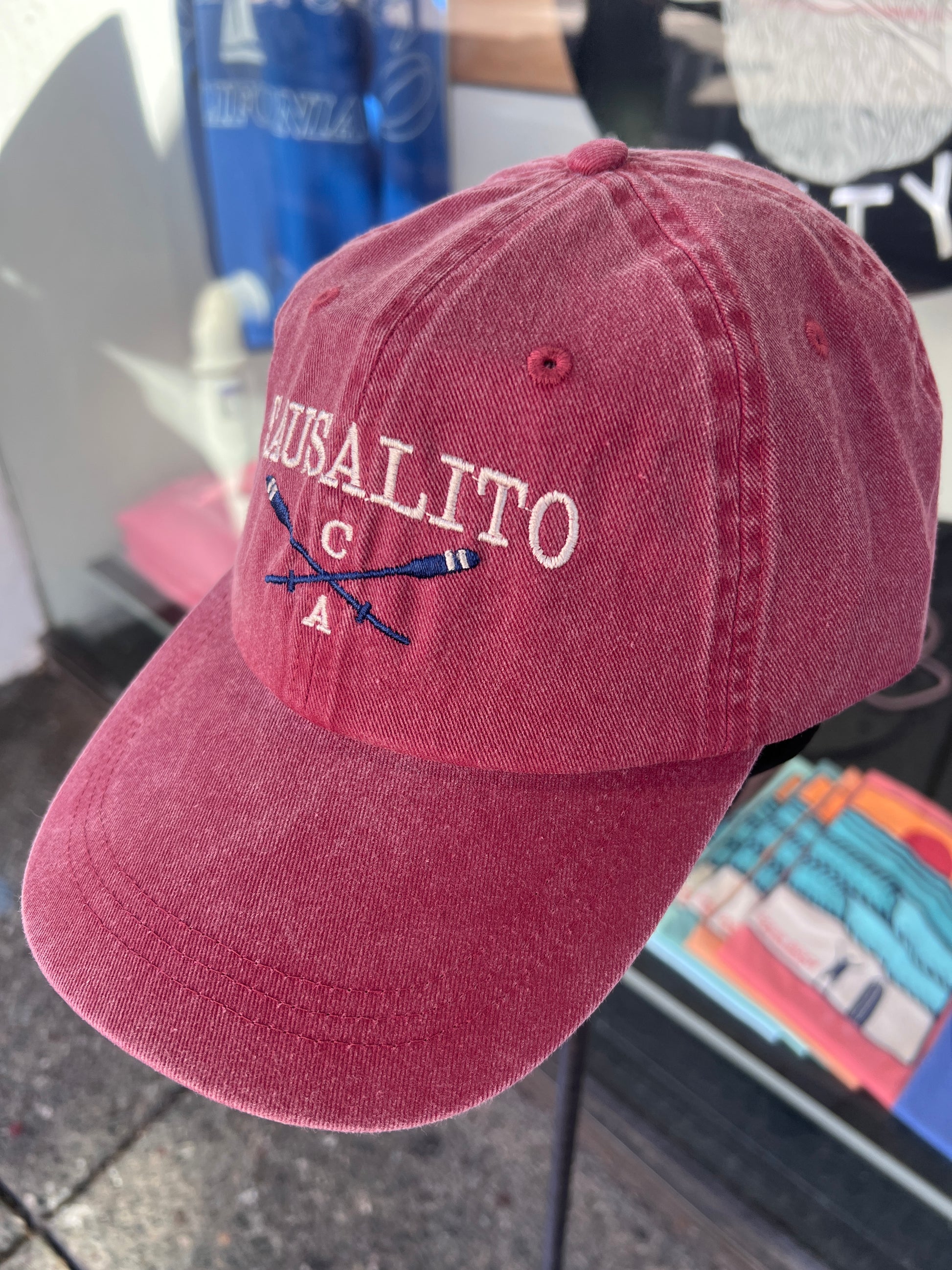 Maroon red washed cotton cap featuring embroidered "SAUSALITO CA" text and crossed blue rowing oars.