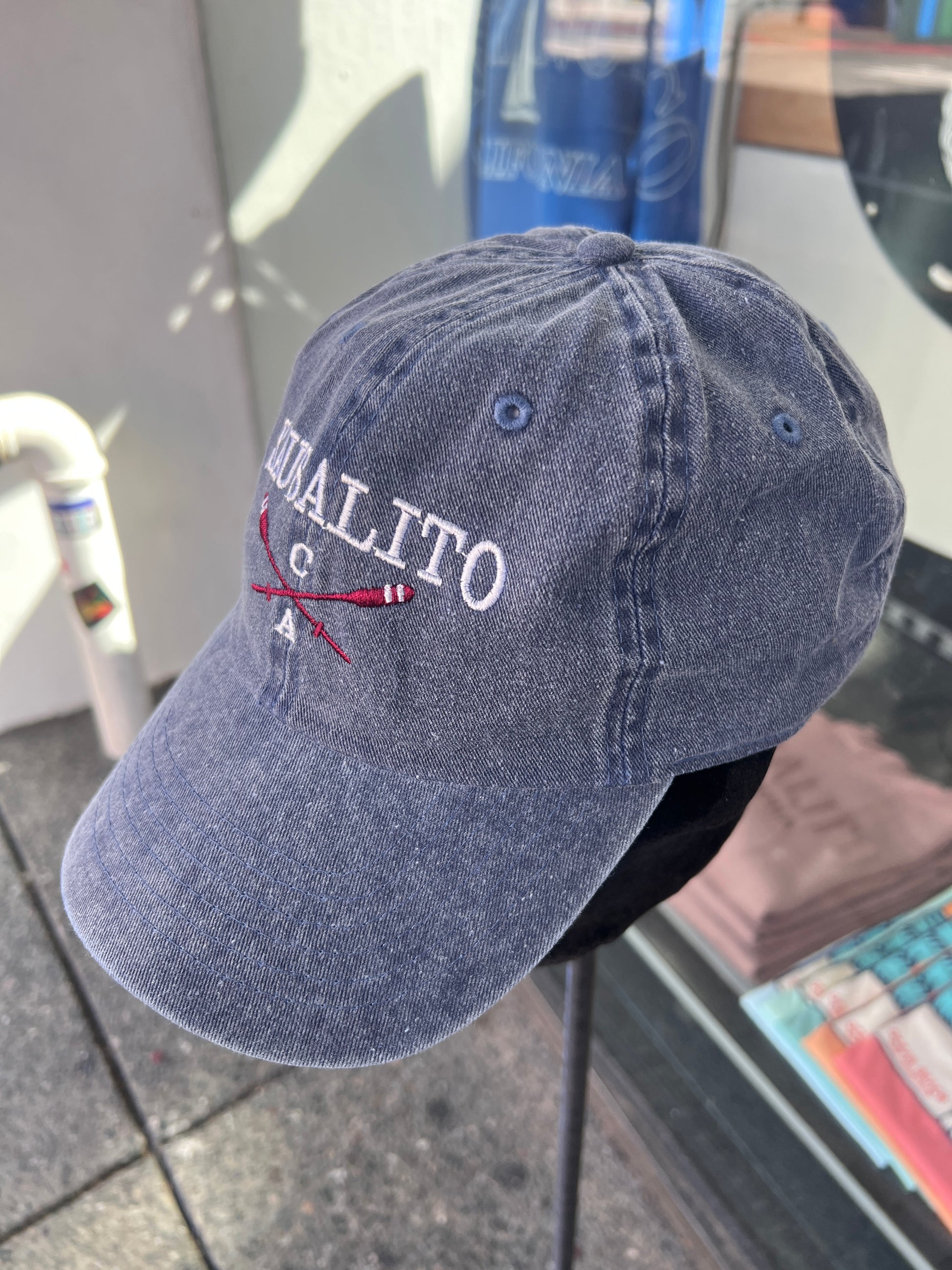 Navy blue washed cotton cap featuring embroidered "SAUSALITO CA" text and crossed red-and-white rowing oars.