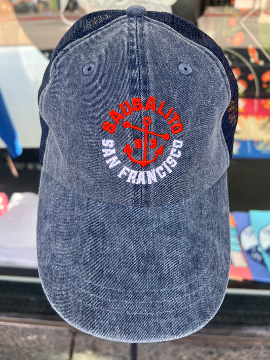 Blue washed denim trucker hat featuring an embroidered orange and white "SAUSALITO SAN FRANCISCO" anchor design with navy blue mesh back.