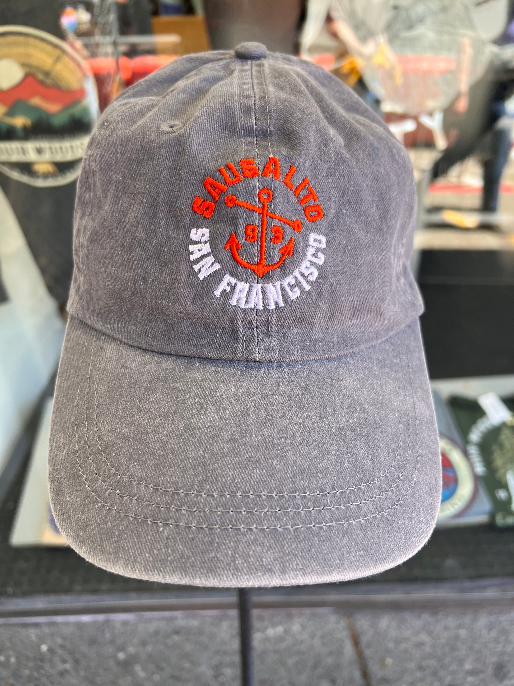 Front view of a vintage grey washed cotton baseball cap featuring an embroidered orange anchor with Sausalito and San Francisco text and the incorporation year 1893.