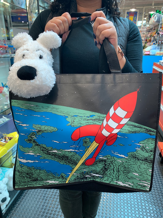 Tintin Moon Rocket waterproof tote bag with Snowy plush, featuring colorful rocket launch illustration, held in store setting