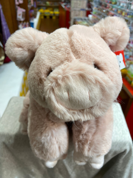 Soft, plush Gund Hamlet pig toy with blush pink fur, curly tail, and snout, displayed in store setting