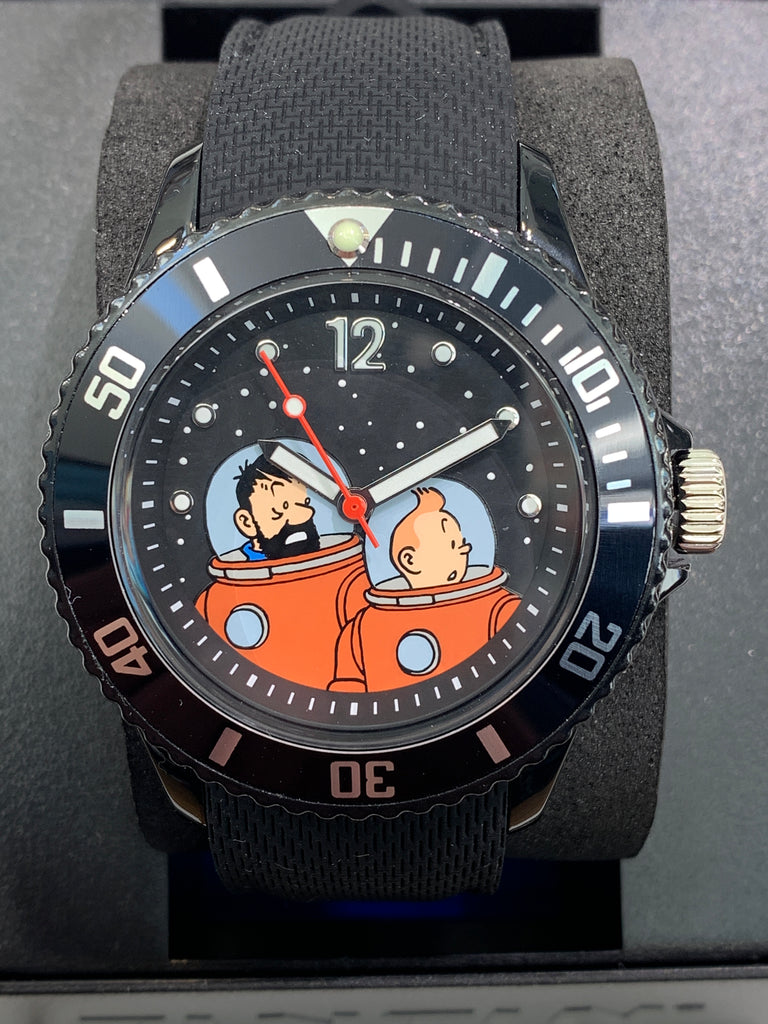 Long before Neil Armstrong took his first step on the moon, Herge had placed  Tintin and Captain Haddock there. Moulinsart celebrates the 50th anniversary of the moon landing with this aviator style watch.   The textured silicon band that is soft and forgiving. Waterproof to 10 ATM. Face of the watch is 30mm (1.2") across and the band is 221.5mm (8.7") long. Battery run.
