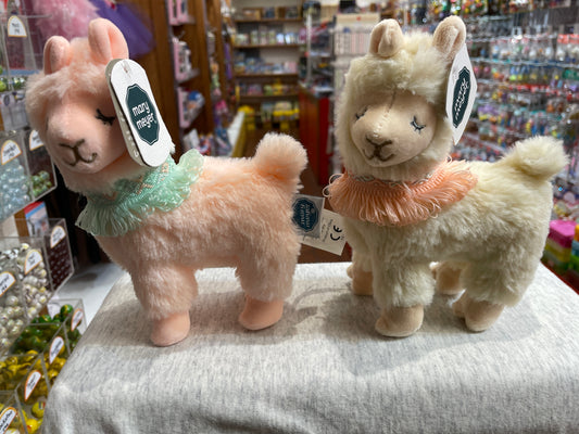 Mary Meyer Lexi Llama plush toys in pink and cream, with colorful neck scarves, displayed in a toy store
