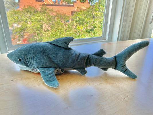Folkmanis 23" grey shark puppet on wooden table, realistic plush toy with movable mouth and detailed fins