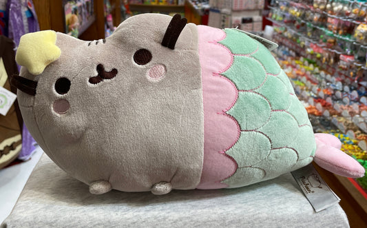 Gund Pusheen mermaid plush toy with gray cat body, pastel mermaid tail, and starfish bow, displayed in store