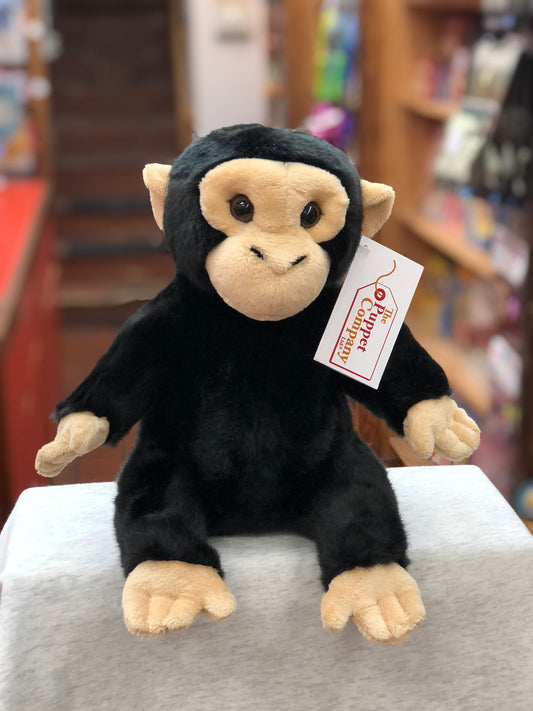 Cuddly full-bodied chimp puppet with black fur and tan face, sitting on display with Puppet Company tag