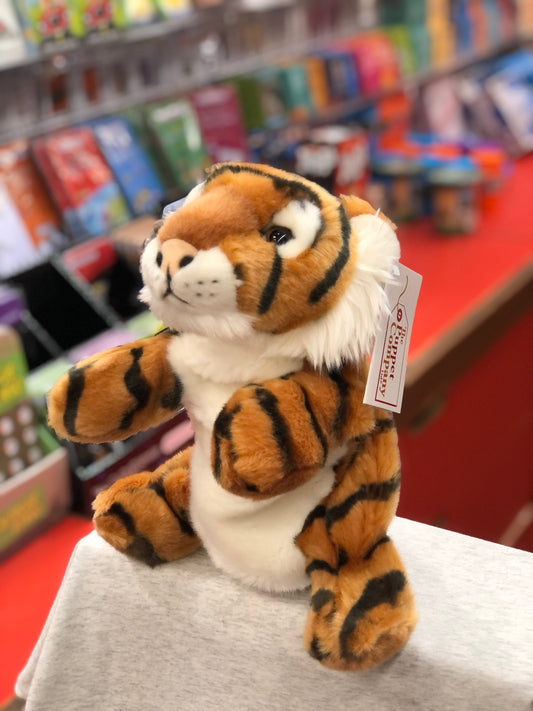 Cuddly tiger puppet from The Puppet Company, featuring soft orange fur with black stripes, displayed in a toy store setting