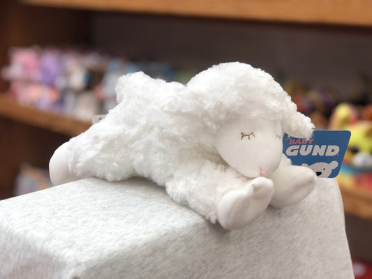 Soft white Gund Baby Winky Lamb rattle toy on display, featuring plush fur and closed eyes, with product tag visible