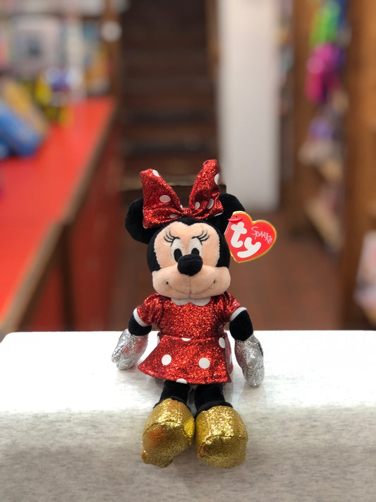 Ty Minnie Mouse plush toy with red sparkle dress, gold shoes, and signature bow, displayed on store shelf