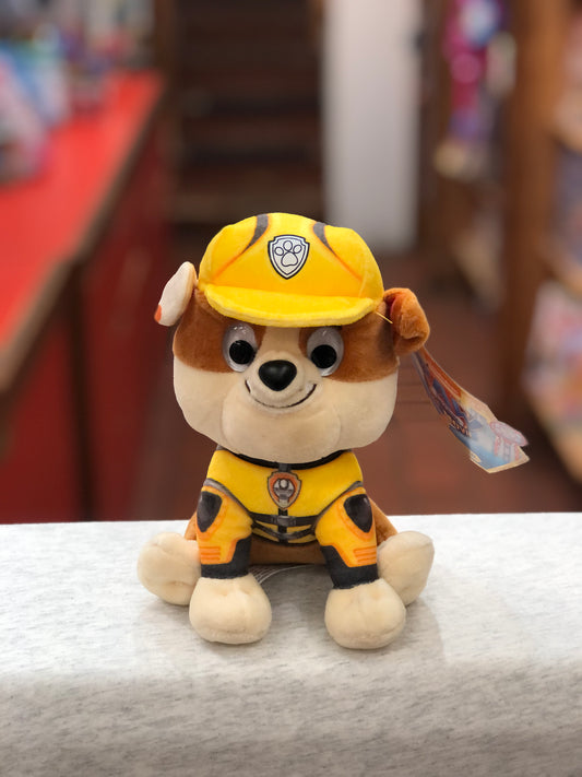 Gund Paw Patrol Rubble plush toy in yellow construction uniform, smiling with big eyes, sitting on white surface