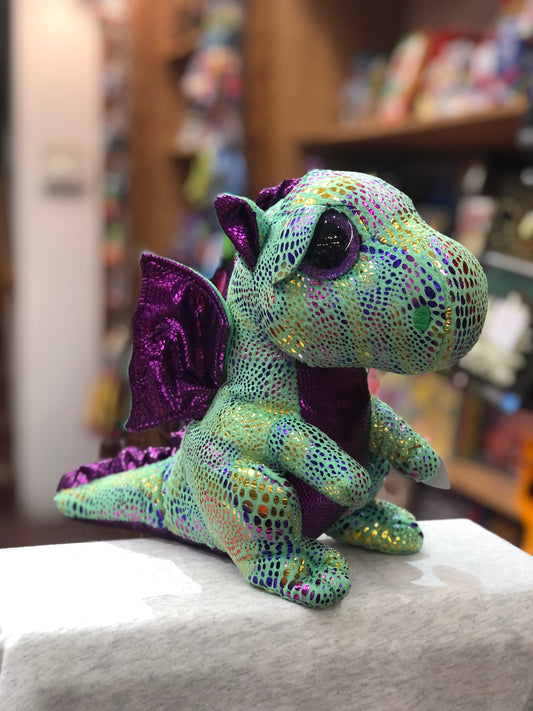 Colorful Ty Beanie Boo Cinder dragon plush with sparkly green body, purple wings, and large eyes, sitting on display