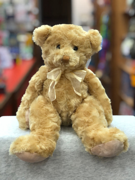 Soft golden teddy bear plush with bow, seated on gray surface, cuddly 12-inch Douglas stuffed animal for all ages