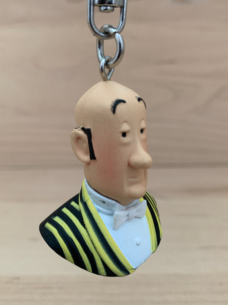 Key chain bust of Nestor, Captain Haddock's loyal butler and keeper of Marlinspike Hall.   The PVC figure is 4cm (1.6") tall. Snap hook closure with swivel.