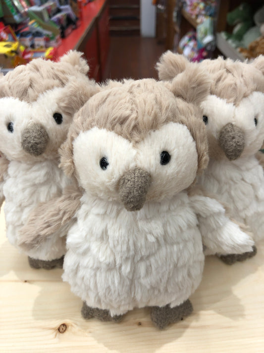 Soft, cuddly Puttling owl plush toys with beige and white fur, sitting together on a wooden surface in a toy store