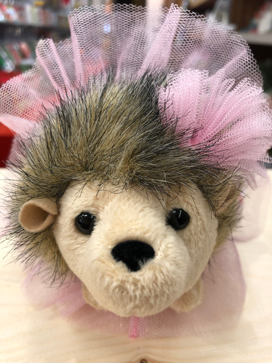 Adorable hedgehog plush toy wearing pink tutu, closeup of soft face with spiky fur and expressive eyes