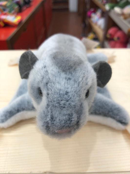 Cuddly gray sugar glider plush toy with soft fur and big eyes, displayed on wooden surface in toy store setting