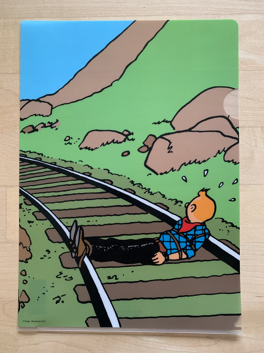 Tintin in America A4 file folder showing cartoon character tied to train tracks in perilous scene from comic adventure