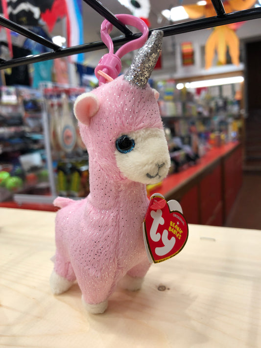 Pink sparkly Ty Beanie Baby llamacorn plush clip with blue eyes and silver horn, displayed in toy store