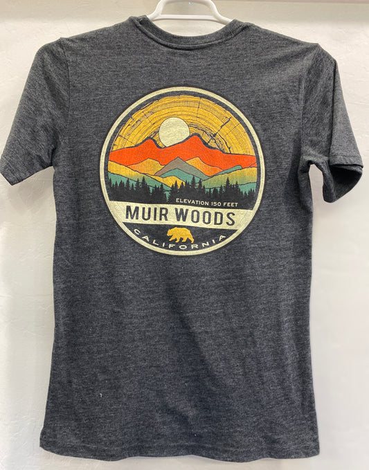 Charcoal gray heather unisex t-shirt featuring a circular graphic emblem on the front with a yellow full moon, orange and yellow mountains, a green silhouette of a redwood forest, and a gold California bear logo at the bottom with the text "Muir Woods California, Elevation 150 Feet".