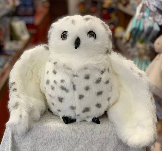 Folkmanis Snowy Owl hand puppet with soft white feathers, spotted belly, and large eyes, displayed in a toy store setting