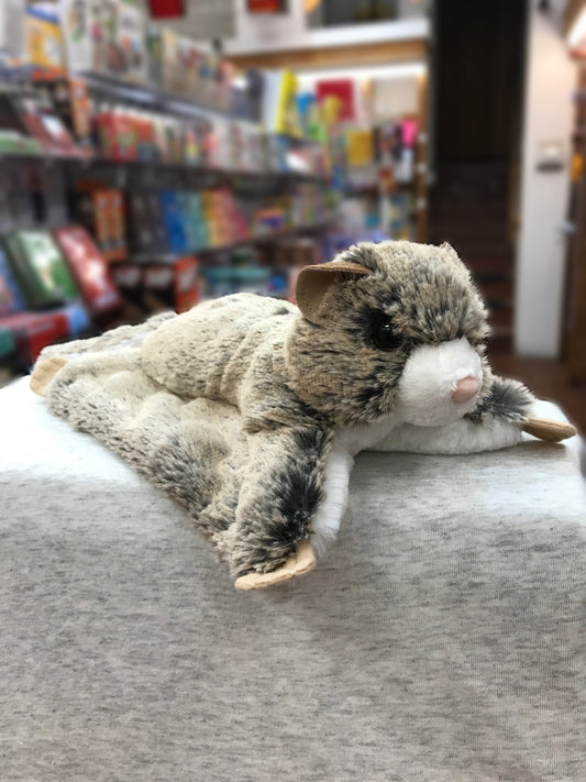 Realistic Douglas Jumper flying squirrel plush toy with soft brown fur and outstretched paws, displayed in a bookstore setting