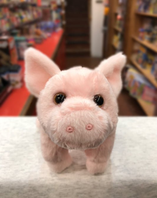 Cute pink pig plush toy with big ears and brown eyes, sitting on display in a toy store