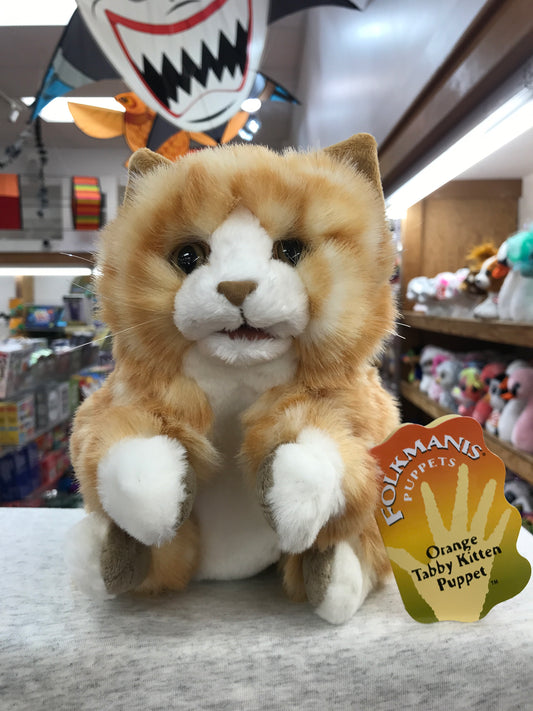 Folkmanis orange tabby kitten puppet with soft fur and whiskers, displayed in toy store with product tag visible
