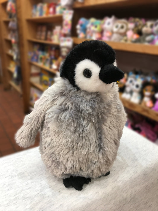 Adorable plush penguin chick toy with soft gray body and black-and-white face, displayed in a toy store setting