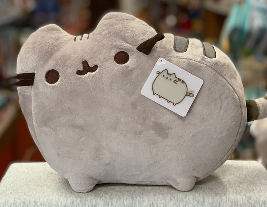 Gund Pusheen plush toy, 12-inch gray cat with cute face, soft fabric, and brand tag, displayed in store
