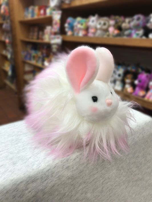 Cute pink and white Douglas Puff Bunny plush toy with fluffy fur, displayed in a toy store with other stuffed animals on shelves