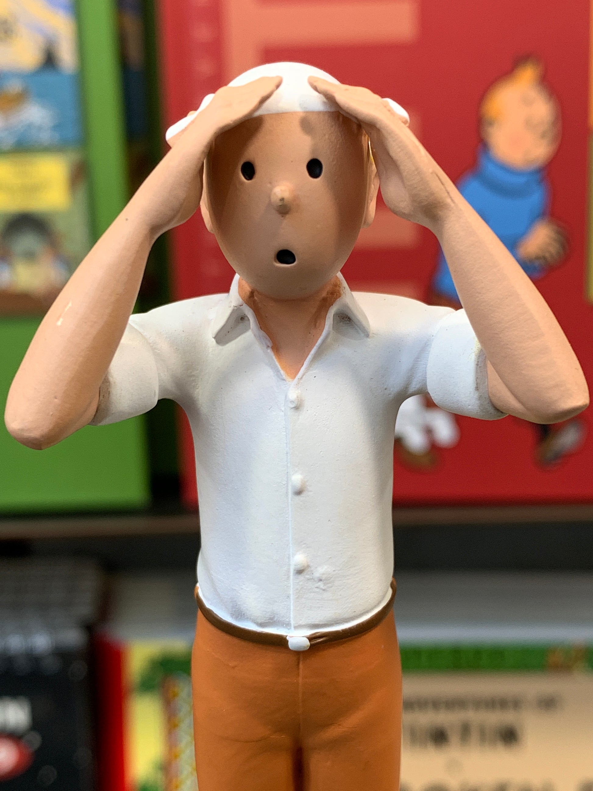 Close-up front view of the Tintin 12cm resin figurine from "The Crab with the Golden Claws," highlighting his wide-eyed, worried facial expression with his hands clutching his head over a white desert headscarf and button down shirt.