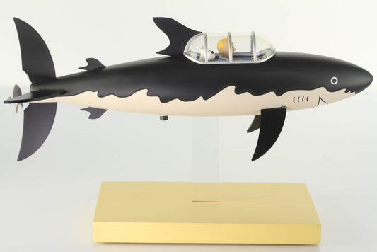 Tintin shark submarine collectible model from Red Rackham's Treasure Icons Collection, black and white shark-shaped vessel with a clear dome cockpit on a yellow display stand.
